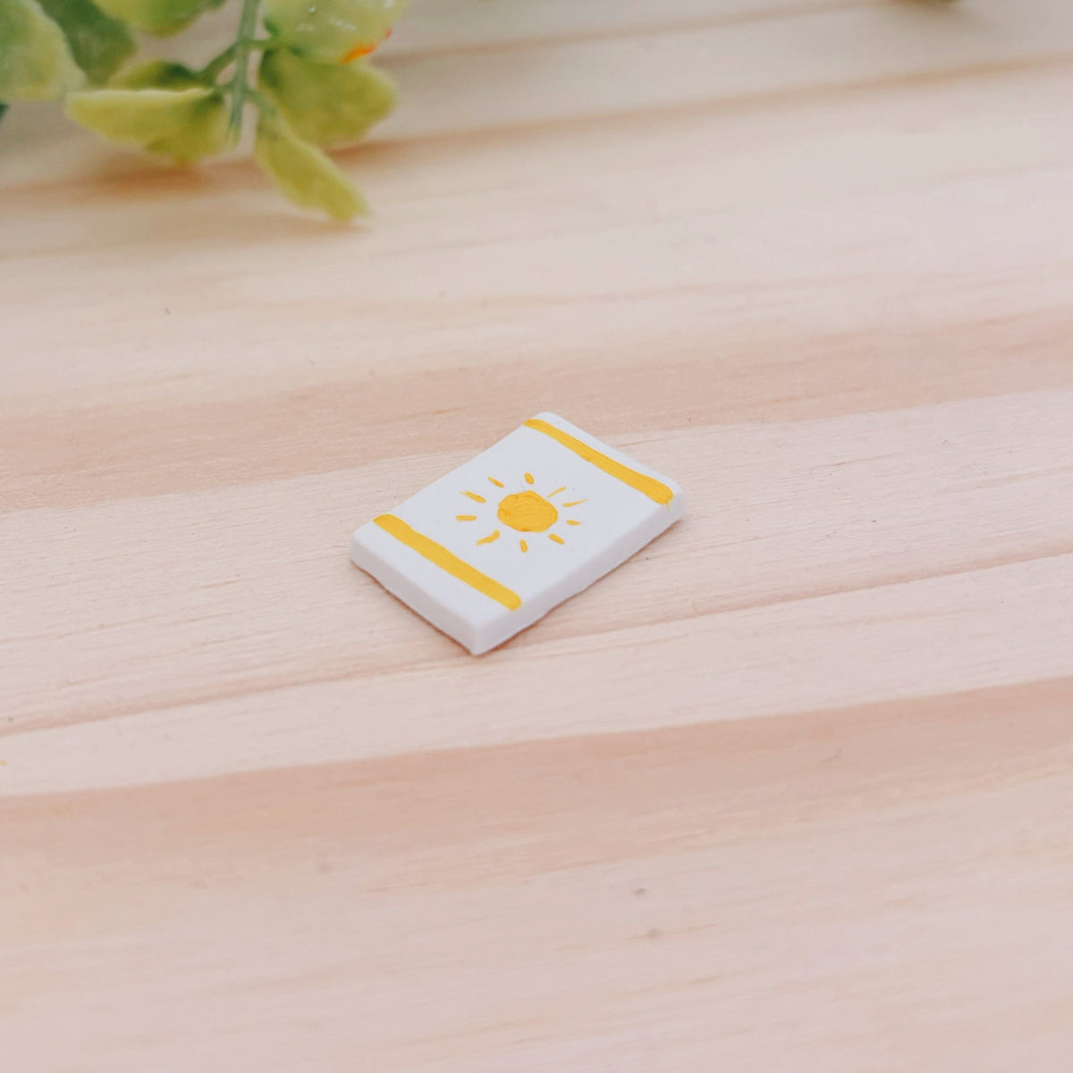Handmade clay miniature beach towel with a painted sun and stripes pattern