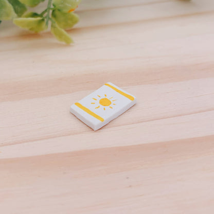 Handmade clay miniature beach towel with a painted sun and stripes pattern